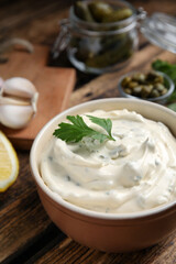 Tasty tartar sauce and ingredients on table, closeup