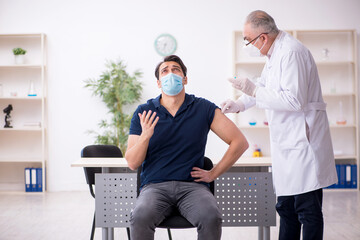 Young male patient visiting old male doctor in vaccination conce