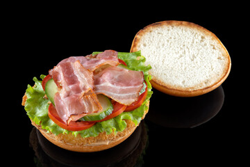 Bacon cheeseburger hamburger isolated on black. BBQ sauce and lettuce.