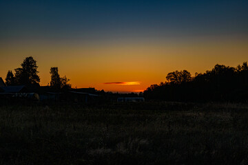 A bright orange cigar-shaped cloud illuminated by the rising morning sun
