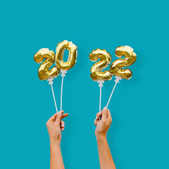 New year number 2022 made of golden balloons on a stick in female hands