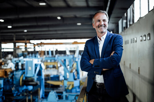 Smiling businessman with arms crossed standing at steel industry