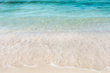 Fototapeta na wymiar Crystal clear sea water and white sand. Waves on the coast. Caribbean sea and tropical holidays. Holiday wallpaper.