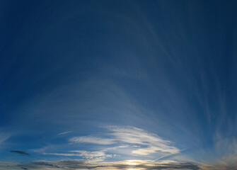 Panorama of the setting sun against a blue sky with openwork clouds