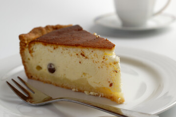 Homemade cheesecake and a cup of coffee on white background