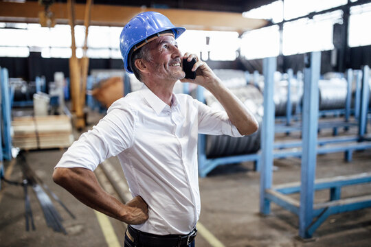 Male engineer with hardhat talking on mobile phone in warehouse