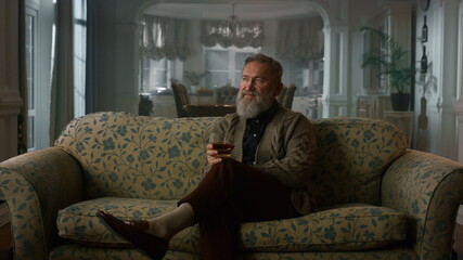 Fototapeta premium Old aged man relaxing with glass whiskey. Rich man thinking retirement life