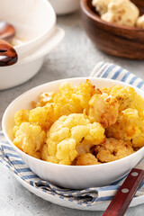 Baked cauliflower in a white bowl on a gray background. Homemade baked cauliflower with butter, cream and garlic. Tasty vegetarian food.