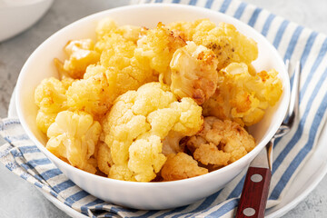 Baked cauliflower in a white bowl on a gray background. Homemade baked cauliflower with butter, cream and garlic. Tasty vegetarian food.