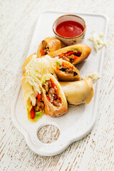  Traditional japanese appetizer, gourmet spring rolls made of fresh vegetables on a white paper background.