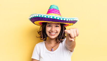 young hispanic woman pointing at camera choosing you. mexican hat concept