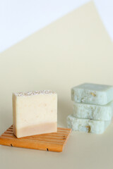 Handmade bars of soap with lavender scent on wooden stand.
