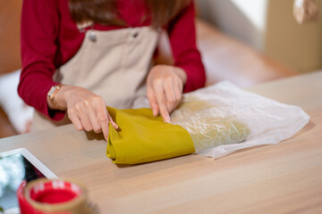 Close up hands of woman put cloth into parcel or plastic bag to prepare for online selling and delivery to customer.