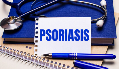 On the table are notepads, a stethoscope, a pen and a sheet of paper with the text PSORIASIS. Medical concept