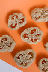 Closeup natural loofah sponges in orange background. - obrazy, fototapety, plakaty