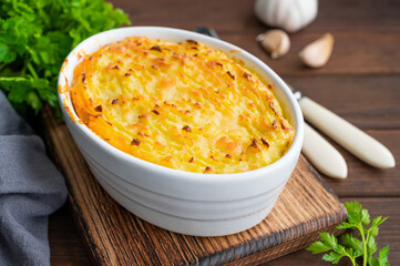Homemade Shepherd's Pie in the casserole dish on a dark wooden background. Traditional British dish...