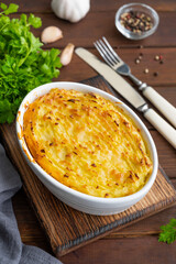 Homemade Shepherd's Pie in the casserole dish on a dark wooden background. Traditional British dish with minced meat and mashed potatoes.