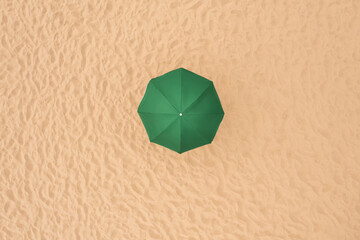 Fototapeta na wymiar Green beach umbrella on sandy coast, aerial view