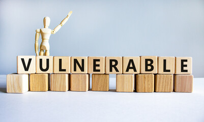 Vulnerable symbol. The word Vulnerable on wooden cubes. Wooden model of human. Businessman icon....