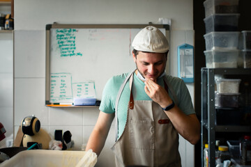A young man in a cap and apron at the baker's job. Problem solving concept.