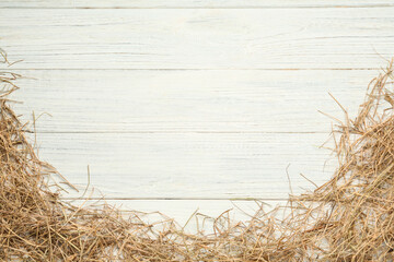 Dried hay on white wooden background, flat lay. Space for text