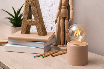 Modern night lamp, books and decor on table indoors. Space for text