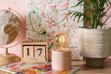 Modern night lamp and decor on table near pink wall