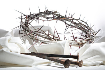 Crown of thorns and nails on a white fabric - the symbols of crucifixion