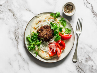 Unleavened flatbread with burger, yogurt sauce, fresh tomatoes and cilantro on a light background, top view