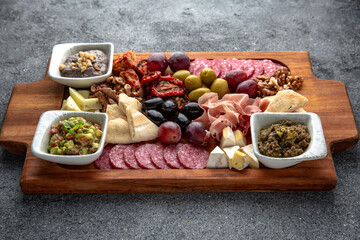 Fototapeta na wymiar Plateau snack for wine. Prosciutto, smoked sausage, olives, cheese, pates. Food for a large company. Ready menu for the restaurant. Neutral gray blue textured background