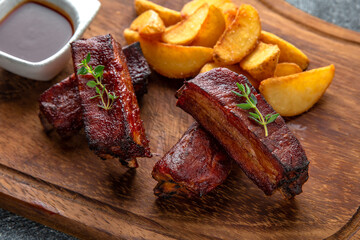 Grilled pork ribs plate with fried potatoes and barbecue sauce. Ready menu for the restaurant. Neutral gray blue textured background