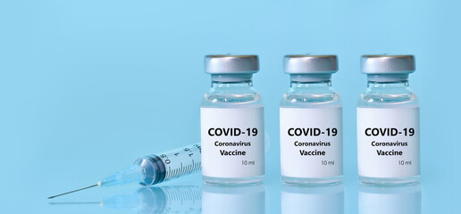 Three vials with a vaccine, a syringe on a blue background.The concept of medicine, healthcare and science.Coronavirus vaccine.Copy space for text..Banner