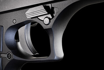 Metal framed handgun trigger that is on a black background - obrazy, fototapety, plakaty