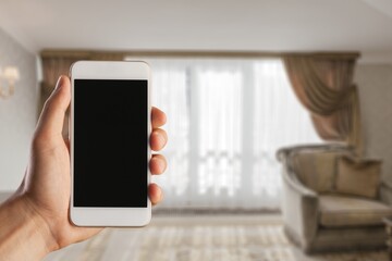 Human hand holding smartphone with white blank empty screen mockup, using smart at home