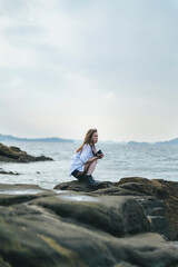 夕暮れの海で写真を撮るカメラ女子