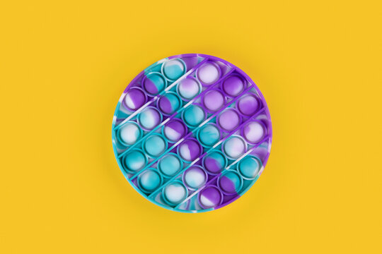 Round popit toy antistress for children and adults on a yellow background