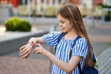 Young kid girl make video call her parents with her pink smartwatch.near school