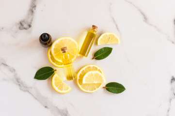 top view of slices of fresh lemon, lemon balm leaves and bright sun essential oil in glass bottles with a cork lid. natural organic cosmetic product.