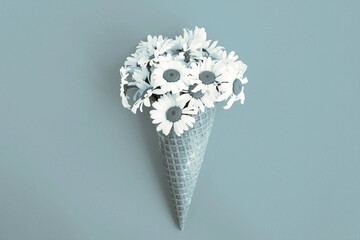 Ice cream cone with chamomile  in the center of the gray  background. Copy space. Flowers concept.
