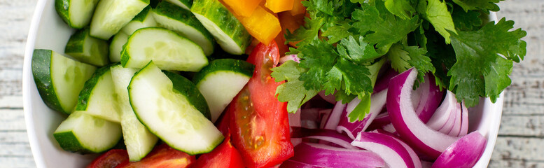 banner of Plate of rainbow salad with different vegetables and herbs in white bowl on white wooden background