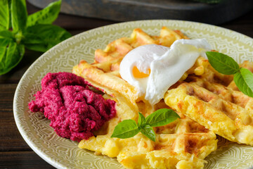 Savory zucchini waffles made of corn and rice flour, poached egg and beet hummus close-up. Healthy vegetarian food.