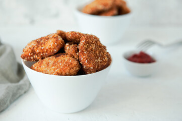 Homemade chicken nuggets with ketchup on a white table, top view, copy space. Fast food concept. Chicken chops.