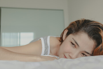 Fototapeta na wymiar Attractive Asian woman lay on the bed feeling relax and cosy in the morning