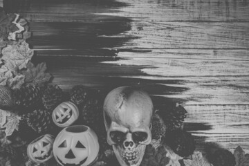 Halloween human skull, Halloween maple leaves on an old wooden table in front of black background...
