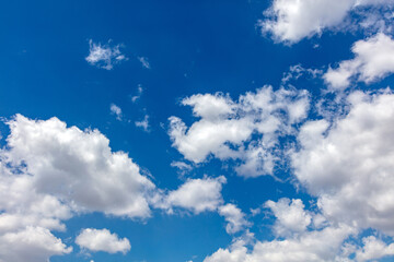 Fluffy cumulus clouds on blue sky background. Cloudscape white and grey color