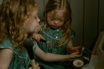 Twin girls with Down Syndrome playing with make up