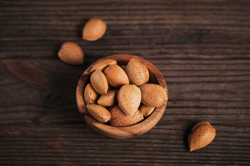 Pile of Almond nuts in a bowl on a dark wooden background