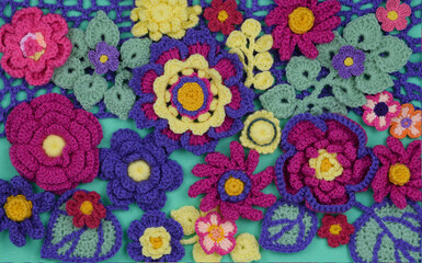 A beautiful crochet multicolored arrangement closeup on a light green background. 
