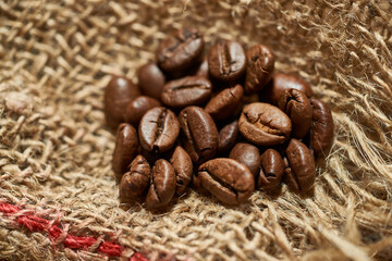 Naklejka premium Roasted coffee beans on piece of sackcloth