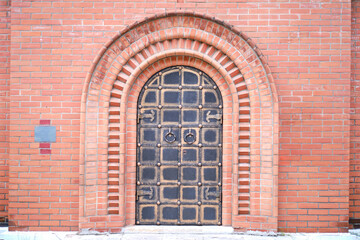 Fototapeta na wymiar The door of a vintage church in the Old Russian style in a red brick wall